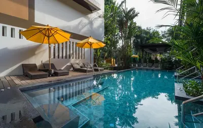 a swimming pool with two umbrellas next to a house at Aonang Princeville Villa Resort & Spa - GHA WellHotel-Halal Certified, Krabi, Thailand in Ao Nang Beach