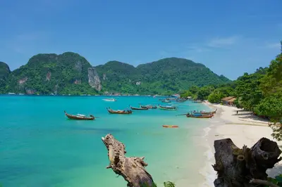 a beach with boats in the water and mountains at Bayview Resort Phi Phi Island - Beach Front Resort in Phi Phi Don