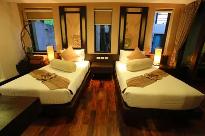 two beds in a room with two windows at Niramaya Villa & Wellness in Ko Yao Noi