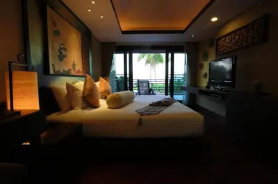 a hotel room with a large bed and a television at Niramaya Villa & Wellness in Ko Yao Noi