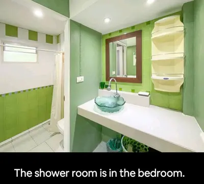 a bathroom with a sink and a shower room with green walls at The Endless Bangtao Residence ST2 in Bang Tao Beach