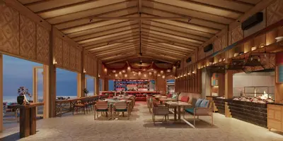 a restaurant with tables and chairs in a room with the ocean at OUTRIGGER Phi Phi Island Resort in Phi Phi Don