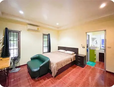 a bedroom with a bed and a green chair at The Endless Bangtao Residence VC 1 in Bang Tao Beach