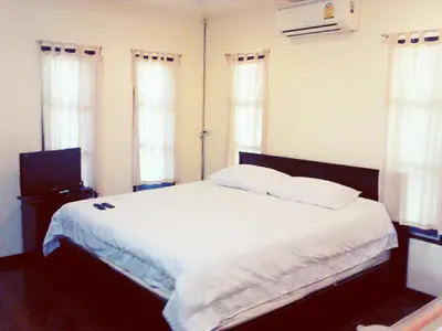 a bedroom with a bed with white sheets and windows at The Endless Bangtao Residence VC 1 in Bang Tao Beach
