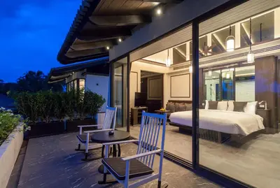a bedroom with a bed and chairs on a balcony at Baba Beach Club Phuket Natai Luxury Pool Villa Hotel by Sri panwa in Natai Beach
