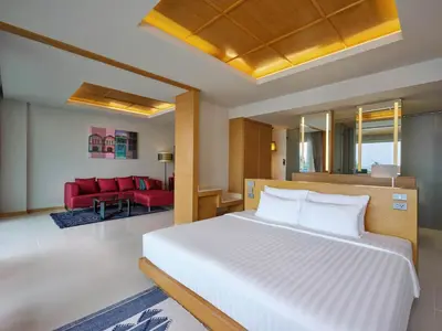a bedroom with a white bed and a red couch at The Kee Resort & Spa in Patong Beach