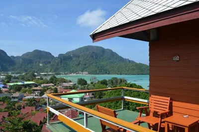 a balcony with two chairs and a view of the water at Phitharom PP Resort in Phi Phi Don