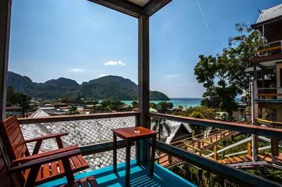 a balcony with a table and chairs and the ocean at Phitharom PP Resort in Phi Phi Don