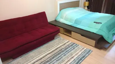 a living room with a red couch and a bed at Naithon condominium A-103 in Nai Thon Beach