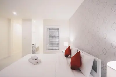 a white bedroom with a bed with two stuffed animals on it at Shunli Hotel - SHA Extra Plus in Phuket Town