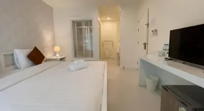 a white bedroom with a large white bed and a television at Shunli Hotel - SHA Extra Plus in Phuket Town