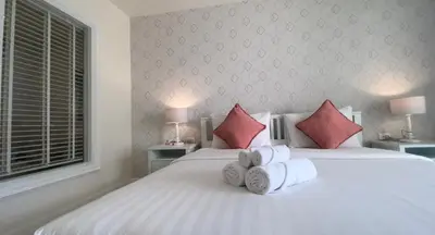 a bedroom with a large white bed with red pillows at Shunli Hotel - SHA Extra Plus in Phuket Town