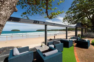 a view of a beach with blue chairs and a table at The Boathouse Phuket-SHA Plus in Kata Beach