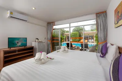 a bedroom with a large white bed with shoes on it at Phuket Sea Resort SHA Extra Plus in Rawai Beach