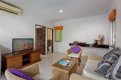 a living room with a flat screen tv and a couch at Phuket Sea Resort SHA Extra Plus in Rawai Beach