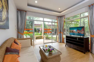 a living room with a couch and a flat screen tv at Phuket Sea Resort SHA Extra Plus in Rawai Beach
