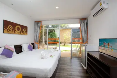 a bedroom with two beds and a tv and a window at Phuket Sea Resort SHA Extra Plus in Rawai Beach