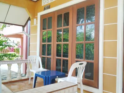 a porch with two white chairs and a blue table at The Endless Bangtao Residence VC 2 in Bang Tao Beach