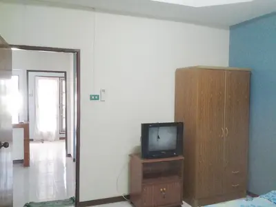 a living room with a tv and a wooden cabinet at The Endless Bangtao Residence VC 2 in Bang Tao Beach