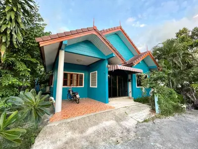 a blue house with a motorcycle in front of it at The Endless Bangtao Residence Wat 1 in Bang Tao Beach