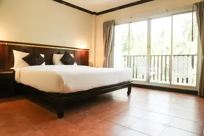 a bedroom with a large bed and a large window at Hotel De Karon in Karon Beach