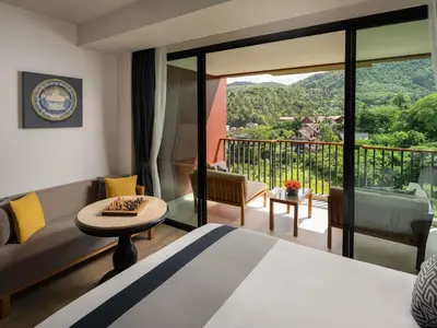 a hotel room with a bed and a balcony at Avista Grande Phuket Karon - MGallery in Karon Beach