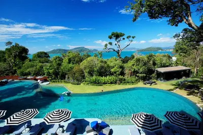 a swimming pool with umbrellas and a view of the water at Sri Panwa Phuket Luxury Pool Villa Hotel in Panwa Beach