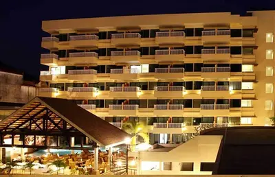 a large white building with tables and chairs in front of it at Palmyra Patong Resort Phuket - SHA Extra Plus in Patong Beach