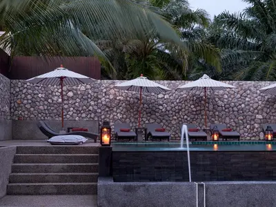 a swimming pool with umbrellas and chairs and a fountain at De Malee Pool Villas in Ao Nang Beach
