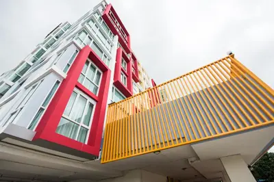 a red and white building with a yellow balcony at Backpacker Street Airport Place in Nai Yang Beach