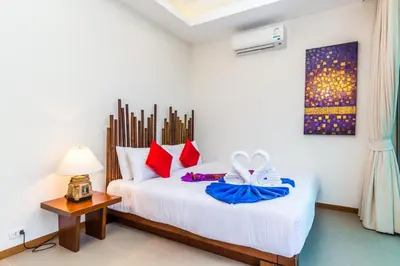 a bedroom with a white bed with red pillows at Ka villa private pool & maid by Lofty in Rawai Beach