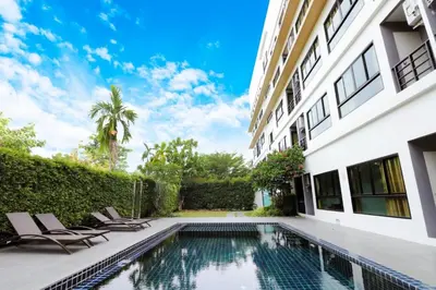 a swimming pool in the backyard of a building with two chairs at S4 Nai Yang Beach - Near Phuket Airport in Nai Yang Beach