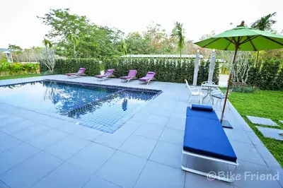 a swimming pool with purple chairs and an umbrella at S4 Nai Yang Beach - Near Phuket Airport in Nai Yang Beach