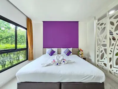 a bedroom with a white bed with a purple wall at S4 Nai Yang Beach - Near Phuket Airport in Nai Yang Beach