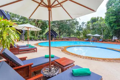 a pool with tables and chairs and an umbrella at Kamala Beach Estate Resort - SHA Extra Plus in Kamala Beach