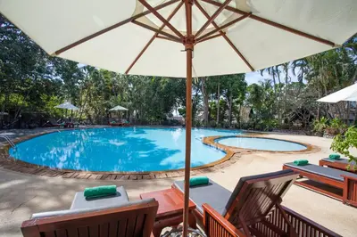 a swimming pool with an umbrella and some chairs and a table at Kamala Beach Estate Resort - SHA Extra Plus in Kamala Beach