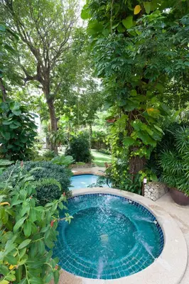 a swimming pool in the middle of a garden at Kamala Beach Estate Resort - SHA Extra Plus in Kamala Beach