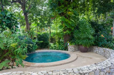 a swimming pool in a garden with trees and plants at Kamala Beach Estate Resort - SHA Extra Plus in Kamala Beach