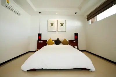 a bedroom with a white bed with yellow pillows at Two Villas HOLIDAY - Oxygen Style Bangtao Beach, Phuket in Bang Tao Beach