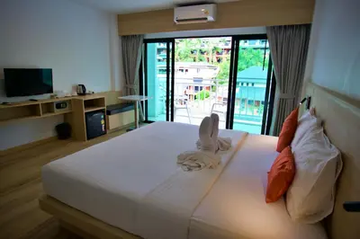 a bedroom with a large white bed with a balcony at Platinum Hotel and Apartments in Patong Beach
