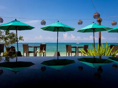 a table with umbrellas and chairs on the beach at Elixir Resort Koh Yao Yai - SHA Plus in Ko Yao Yai