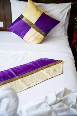 a bed with purple and gold pillows on it at Thai Siam in Patong Beach