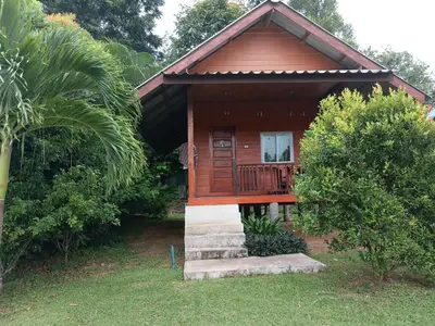 a small wooden house with a porch and a tree at Cha Bungalow in Ko Yao Noi