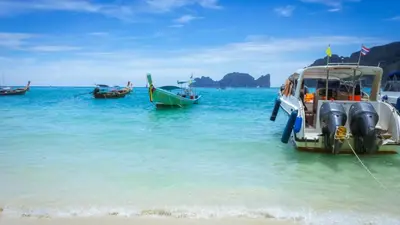 a group of boats docked on a beach in the water at Phi Phi Andaman Beach Resort in Phi Phi Don