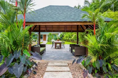 a pavilion with a table and chairs in a garden at Villa Raeya in Ao Nang Beach