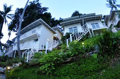 a building with white stairs and palm trees at Uphill Cottage in Phi Phi Don