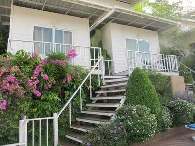 a house with stairs and flowers in front of it at Uphill Cottage in Phi Phi Don