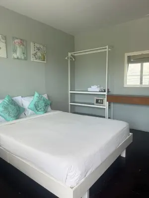 a bedroom with a large white bed with blue pillows at Uphill Cottage in Phi Phi Don