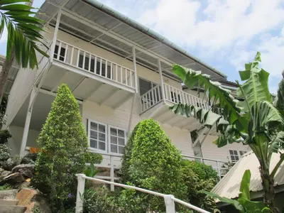 an exterior view of a white house with plants at Uphill Cottage in Phi Phi Don
