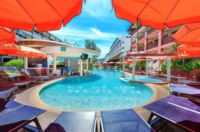 a swimming pool with tables and umbrellas at a hotel at Kata Sea Breeze Resort - SHA Plus in Kata Beach